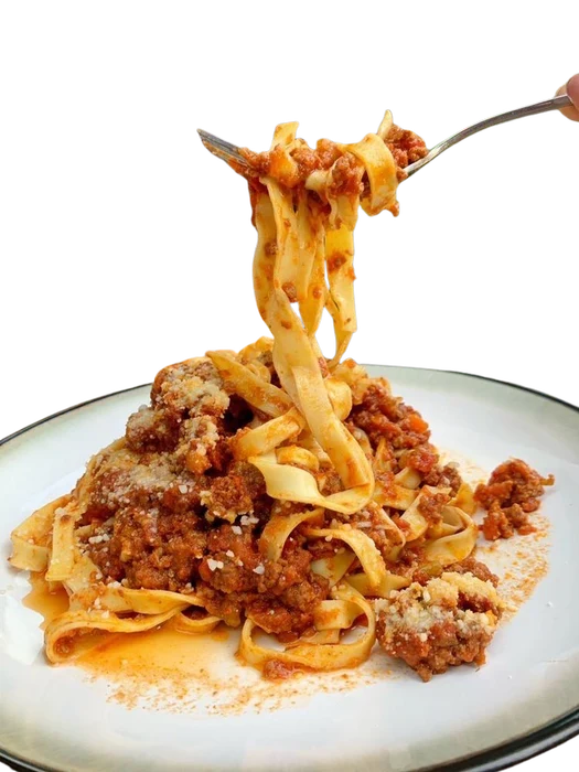 Pasta being lifted from a plate of bolognese